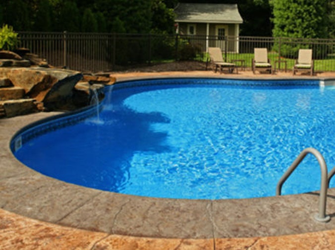 Oval shaped back yard swiming pool with waterfall